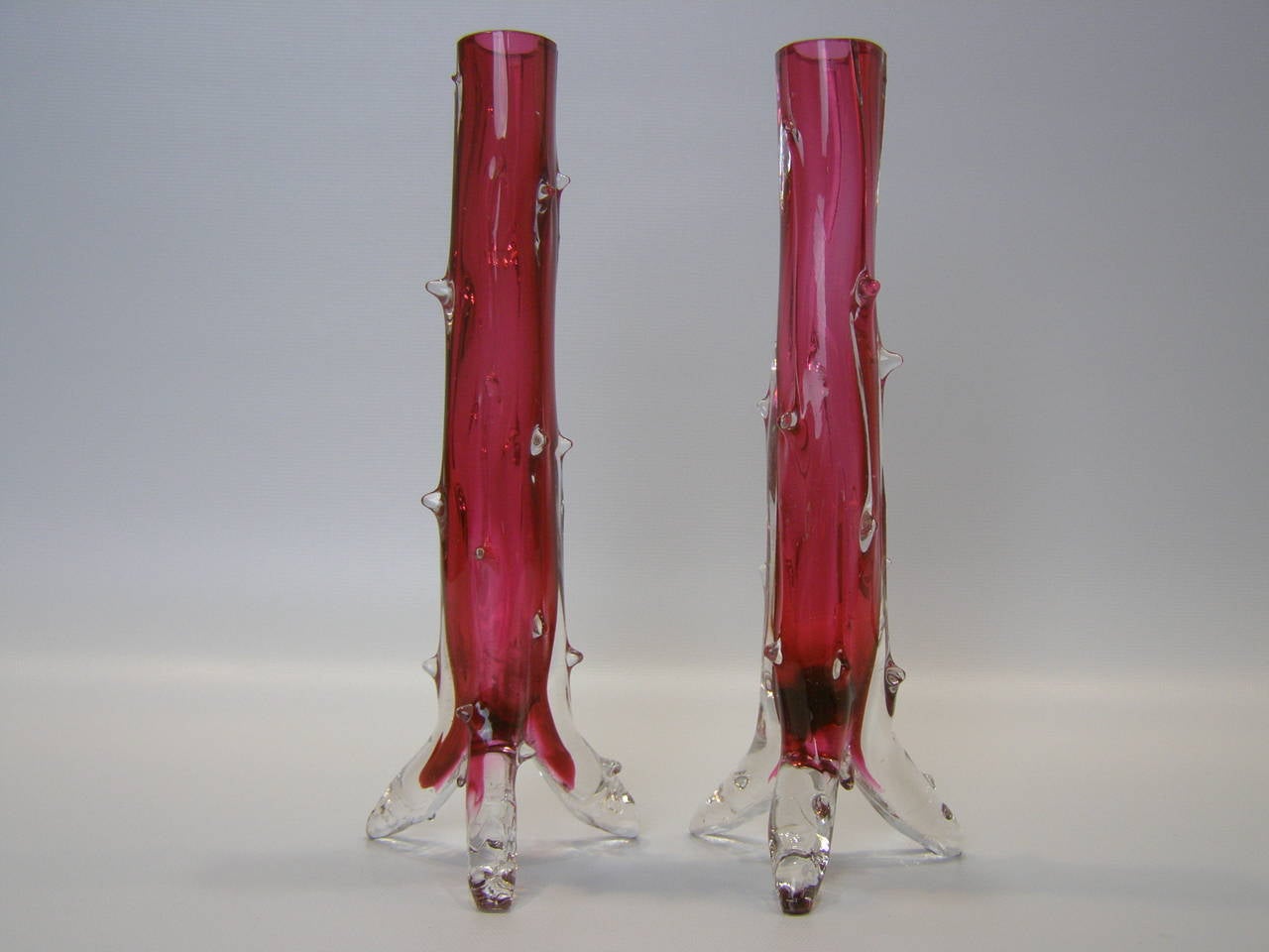 Lovely pair of hand blown bud vases designed to look like cactus's. Cranberry colored glass with clear glass casing and tripod legs. Sold as a pair.
The measurements below show the diameter of the stems; the width including the tripod legs is 3