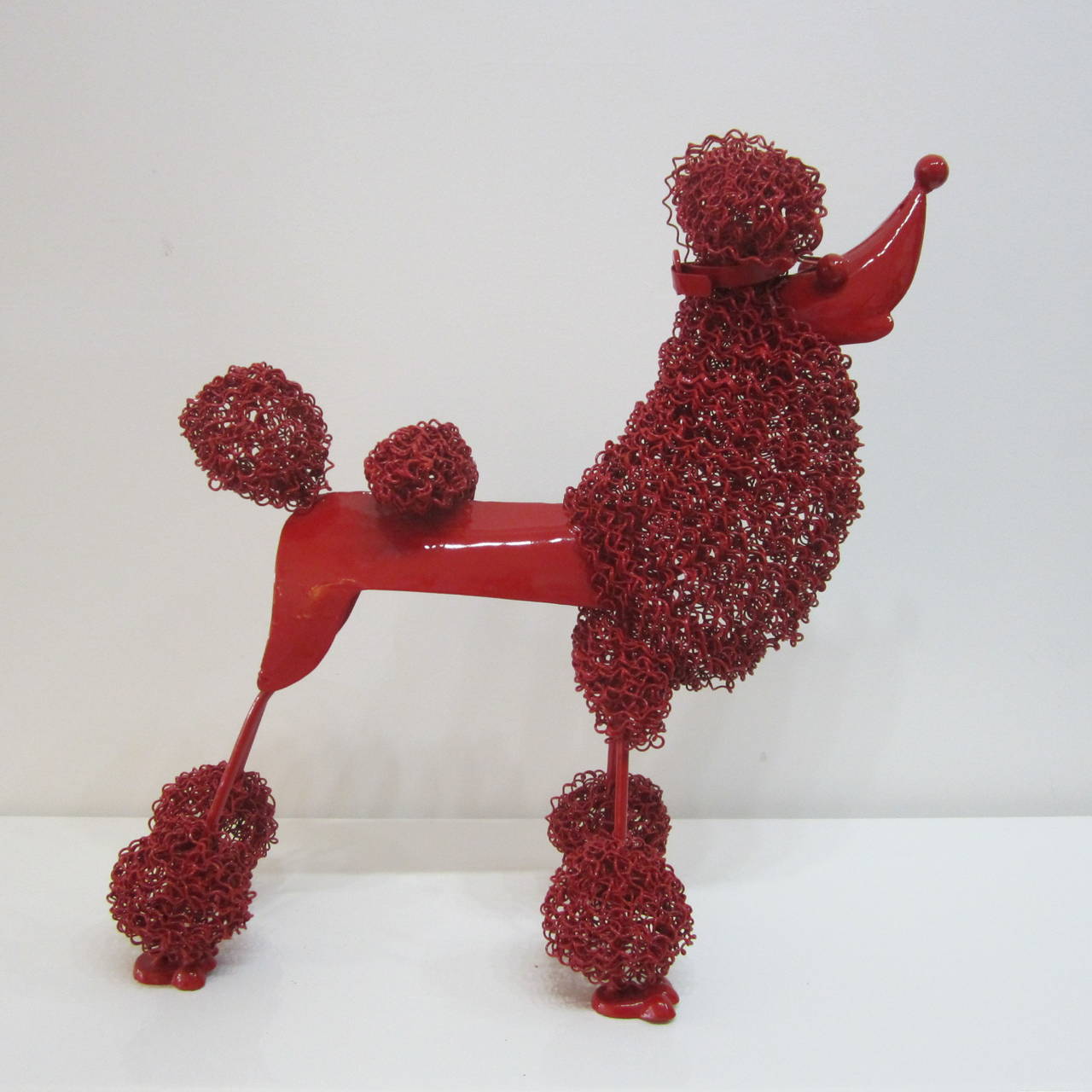 Adorable metal standard poodle sculpture lacquered in fire engine red. Curly wire used as fur and body is all metal.