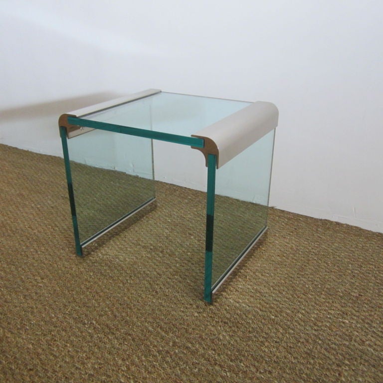 Chic side table fashioned of original thick glass with nickel silvered waterfall sides. Finished at bottom with nickel full length brackets protecting glass from floor. Great for a myriad of decors--a clean chic look.