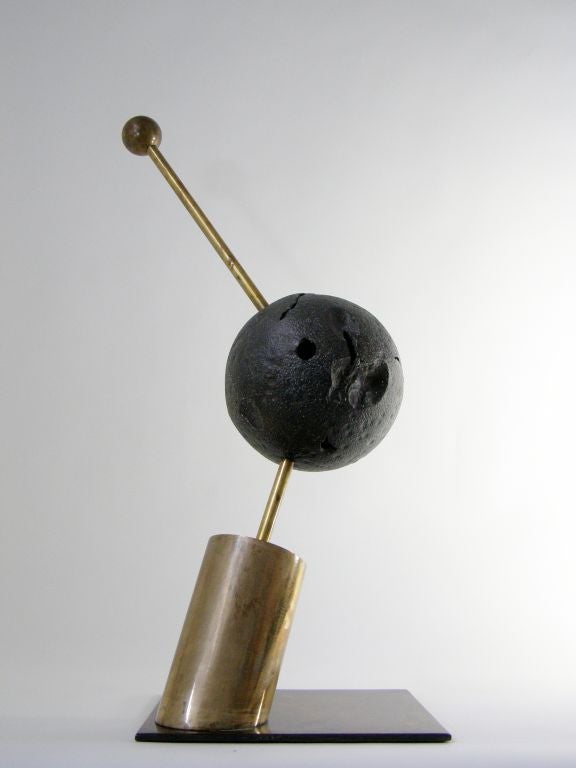 Intriguing sculpture fashioned of bronze and brass. Center galaxy-like ball extends from brass rod connected to cantilevered cylinder resting on substantial flat base. Upper brass rod extends upward and terminates with a smaller galaxy. This