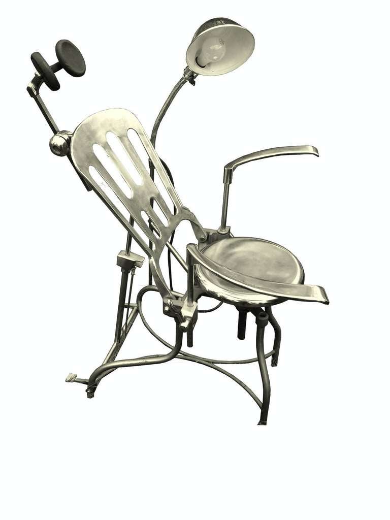 An unusual iron and stainless steel dentist’s armchair with a lamp. A reclining backrest, adjustable armrests and adjustable headrest. Produced from A.S.ALOE COMPANY, ST. LOUIS, MO – USA.