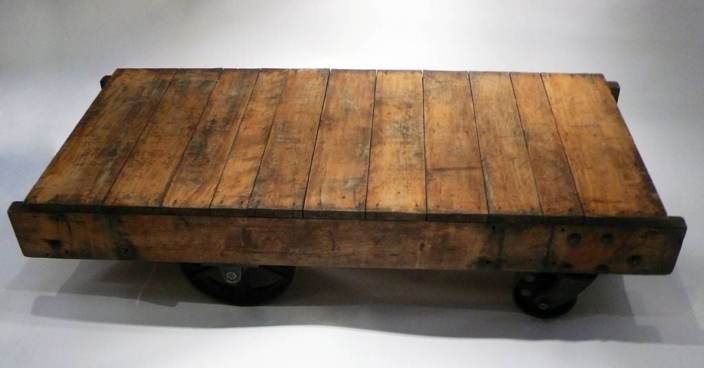 Wooden industrial cart with 4 metal jointed wheels.