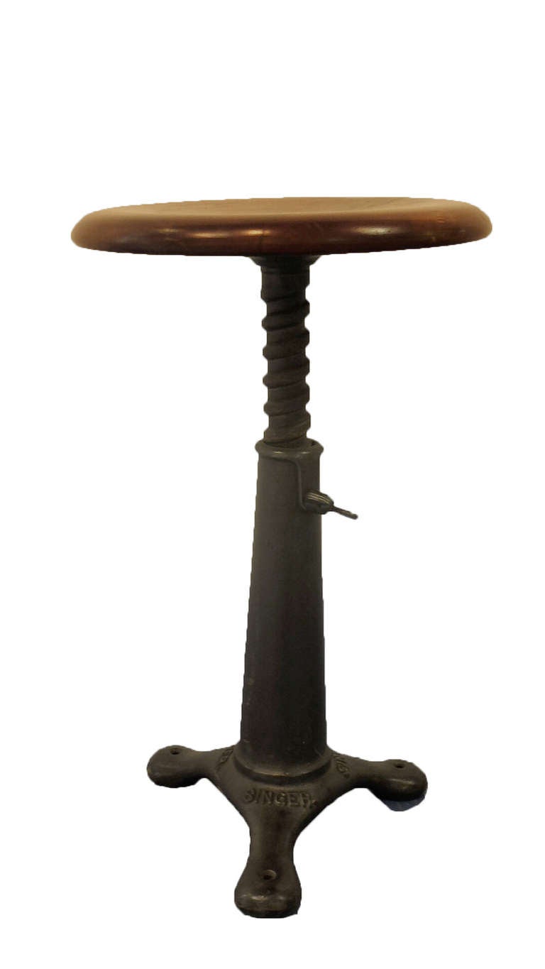In 1910 Singer produced this adjustable stool for the textile industry. The leg is made out of cast iron and the sit is made out of solid wood. Screwing or unscrewing the thick screew we can adjust the size of the stool (height: from 24 to 31