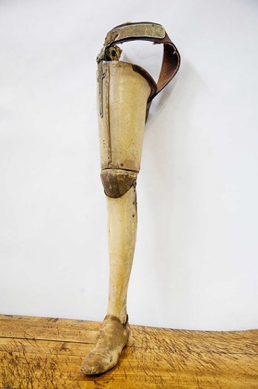 Artificial leg made entirely of light-colored leather with metal and leather belt to hook on. Shoe leather, wood knee. American Civil War period. Usa.