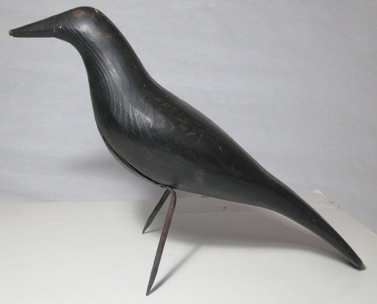 carved solid body crow decoy, wonderful animation, metal eyes, owner stamp, there is some minor damage to the beak.