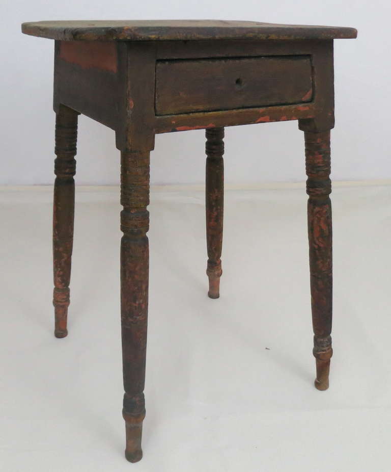 A rare early untouched example of American country furniture. Beautifully formed shaped top held in place by four wrought iron metal pegs. The stand has gracefully splayed turned legs. Overall very dry flaking surface revealing paint history of
