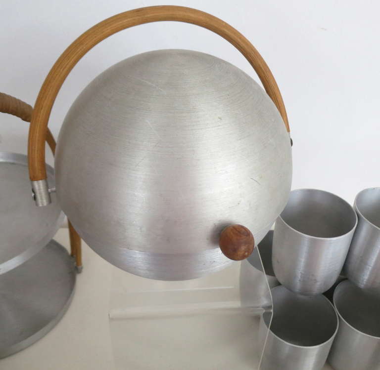 Collection of eleven pieces of spun aluminum serving pieces by the iconic American modernist designer Russel Wright.  Includes the bun warmer, two tiered serving tray, covered cake plate, open server and the pitcher and six tumblers.  Pitcher has
