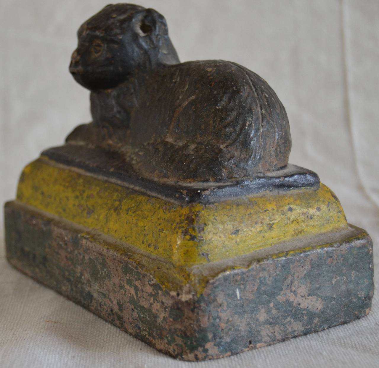 Folk Art modeled polychrome stoneware cat doorstop. This end of day sculpture of a reclining cat has an illegible name painted on the bottom green tier. The cat rests on a second tier painted bright yellow. A rare Folk Art portrait of a cat with a