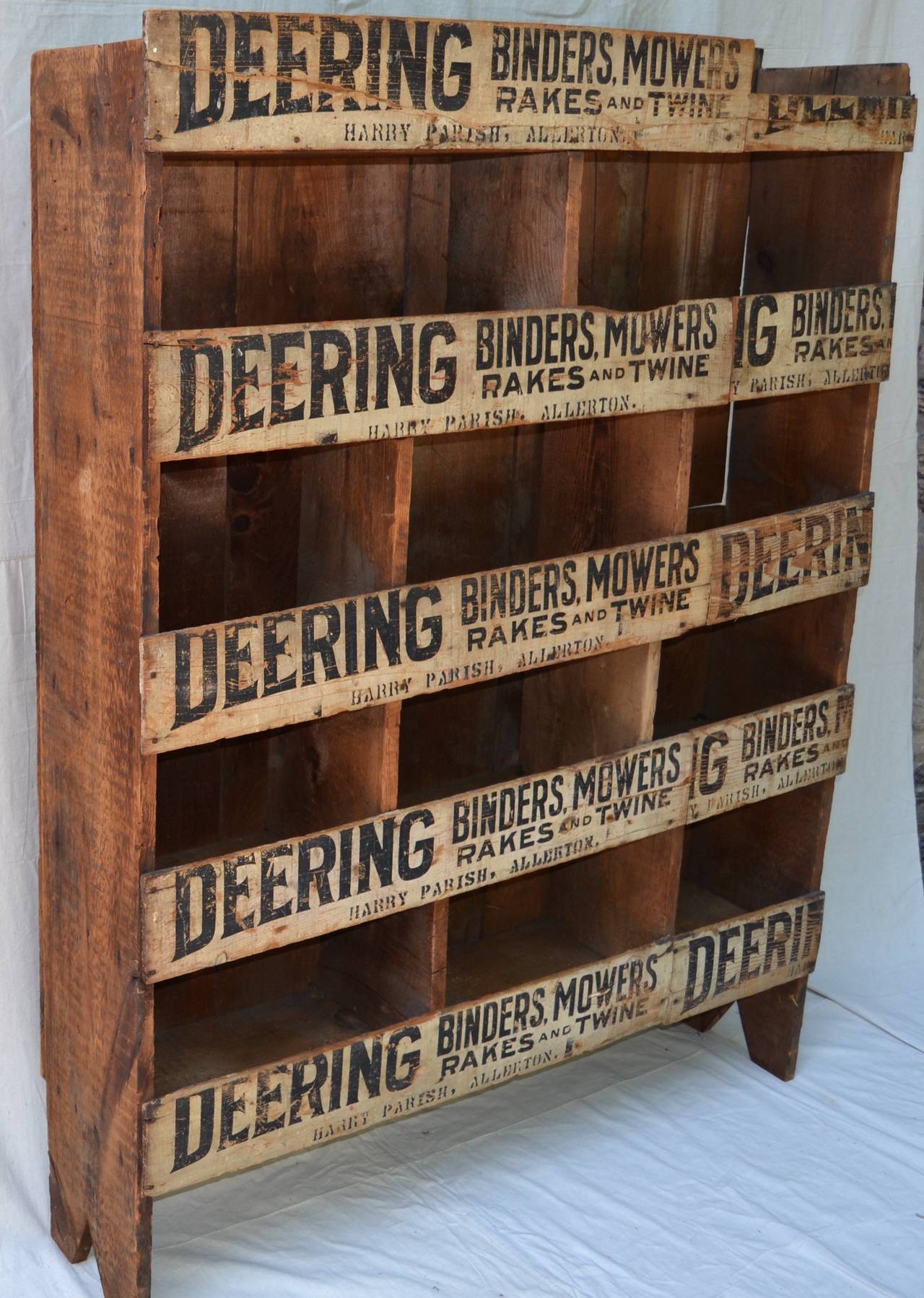 Beautifully graphic storage cabinet from a farm supply store. A well-made inventory sorting cabinet with collaged wooden advertising signs forming the front of the piece. Triangular cutouts are used on the side panels giving additional visual