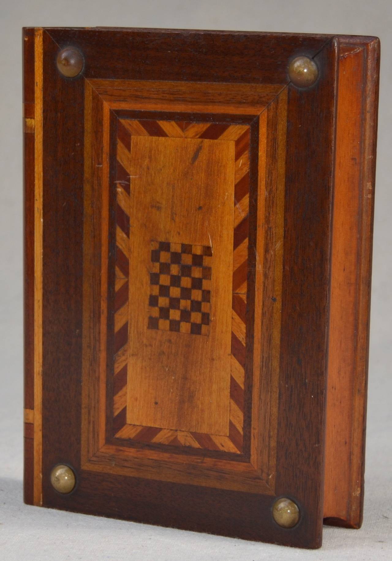 A folk art marquetry book box with a secret opening mechanism. checkerboard design with brass nail heads