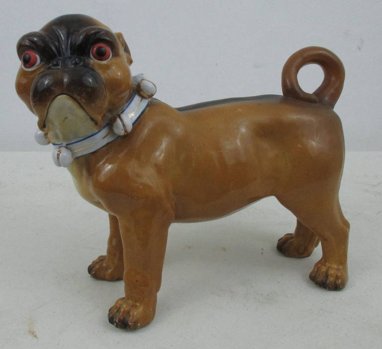 Large pug with bell and bow collar. Probably German. there are marks on the bottom of the feet, un-identified by us