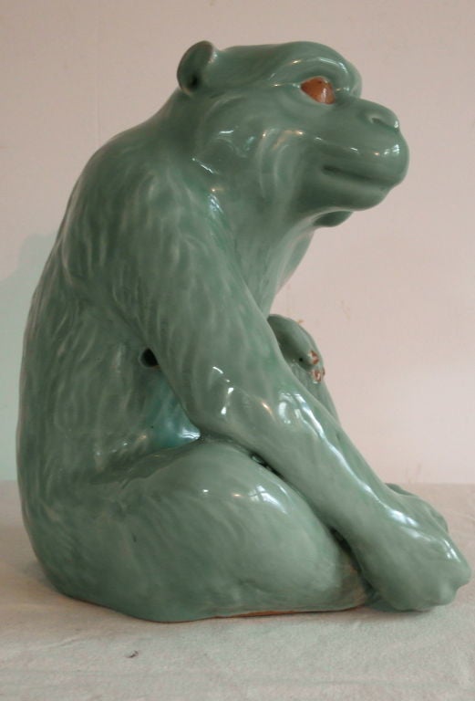 Japanese pottery statue of a monkey with animated stance, celadon glaze and painted details.