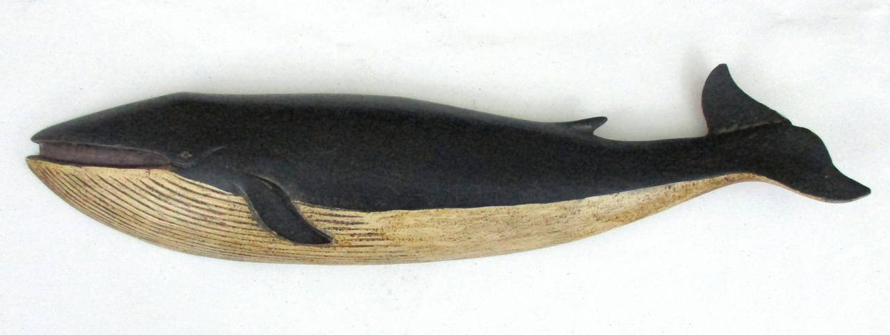Carved and painted wooden whale plaque by the master carver Clark Voorhees (1911-1980). Voorhees captured the spirit and movement of whales in his iconic whale plaques.  Carving has original paint with an inlaid eye and the original brass hanger on