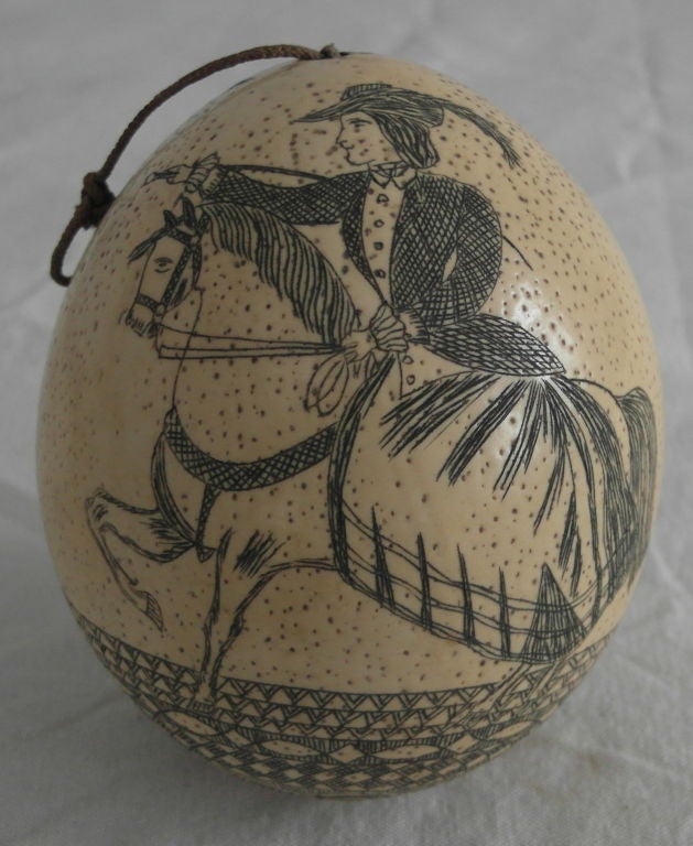 Sailor decorated ostrich egg with three figures, one woman on horseback and two Scottish men wearing plaid, elaborate banded decoration. original macrame miniature rope hanger.