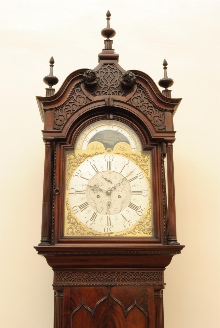 A fine example of a Lancashire mahogany longcase clock, the case with superb flame veneers, blind fret work and carved details. The elegant turned finials to the top of the hood are original. The eight day movement with moon roller. 

Provenance: