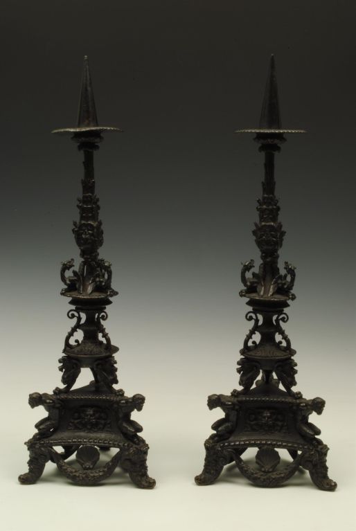 A fine pair of 19th century bronze pricket candlesticks with cast figures and mask feet, in the manner of a 17th century version.