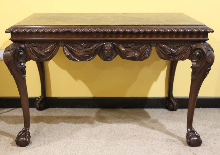An important Irish walnut marble top side table. The frieze carved with swags and in the centre, a head.
