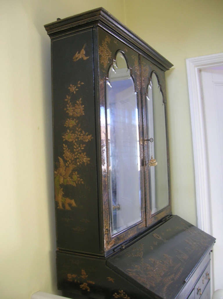 England
William & Mary
A William & Mary black Japanned Bureau Bookcase heightened with gilt chinoiseries. The rectangular ogee moulded cornice above a pair of arched bevelled mirrored doors, enclosing three shelves. A pair of candle slides and a