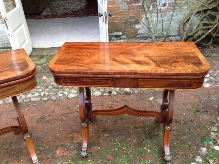 A very good pair of Regency period mahogany tea tables raised on elegant standard ends and inlaid with boxwood stringing, and have metal mounts to the legs. The timber throughout is spectacular flame figured mahogany. The tops rotate on the bases so