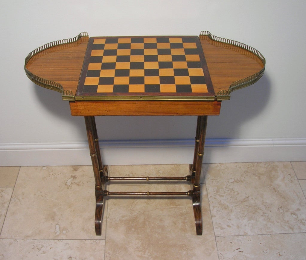 Regency Rosewood and simulated rosewood and parcel gilt Games Table.  The rectangular top with projecting D-shaped end sections with pierced brass galleries.  The centre section with a sliding panel - the reverse inlaid with chequer board and