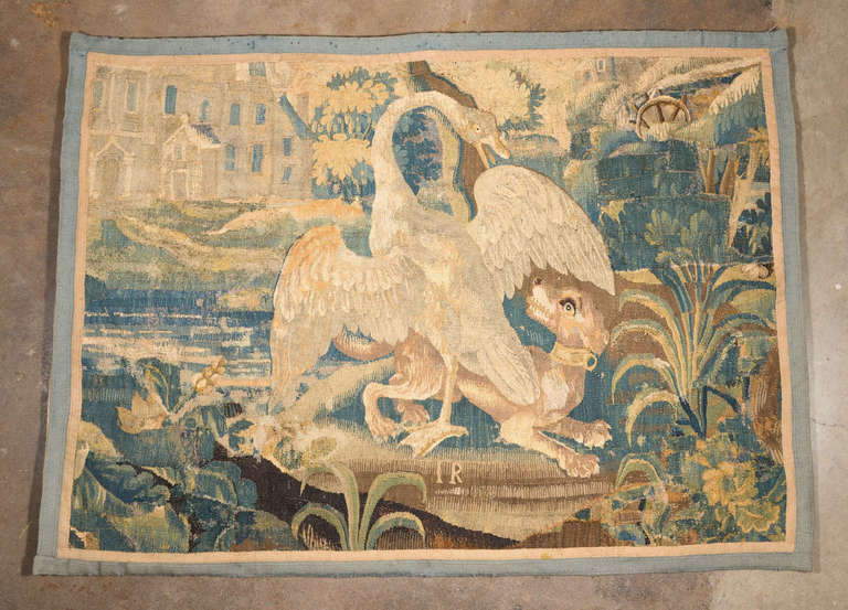 Aubusson tapestry depicting a swan engaged with a dog like creature. Beautiful browns, blues, and cream colors throughout. Grey blue and tan border. In excellent shape. Could use to hide a flat screen TV. The back is lined in fabric with 5 rings 
