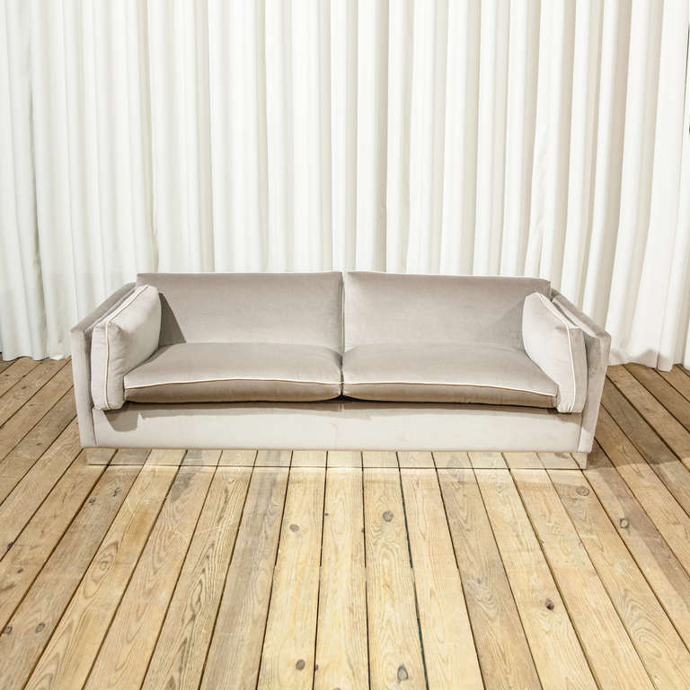 An Upholstered Three Seater Sofa with Chrome Plinth. Newly upholstered in a light grey velvet.