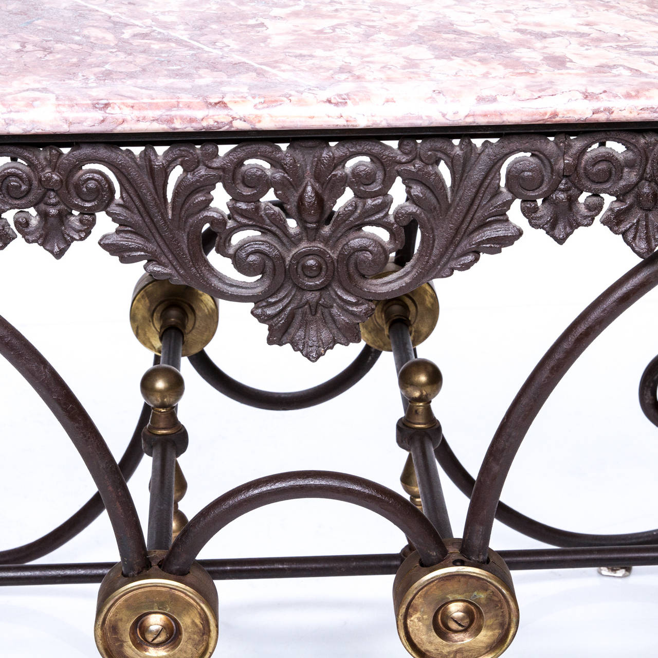 French iron and marble pastry table.

A fine and quality iron base and marble-top French pastry table with decorative apron and scrolled base. Notice the brass round cover plates and finials. Just a sign of the quality of this table, circa 1920s.
