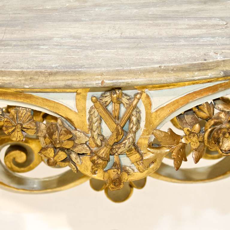 A superb Louis XV style painted and gilded console. Fantastic baroque carvings and highlighted by water gilding. Original paint and a faux marble style painted top. The back is a carved fleur de lis. Stretcher is centered with an urn and the front