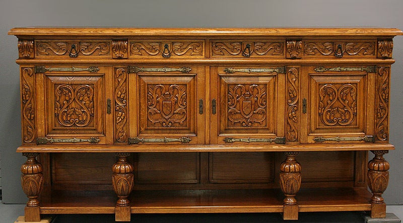 This is a handsome French Renaissance enfilade in a light french oak. Having an open shelf with bulbous turned supports. The four doors are presented with raised carved panels. The two doors in the center have carved crest surrounded by leaves on