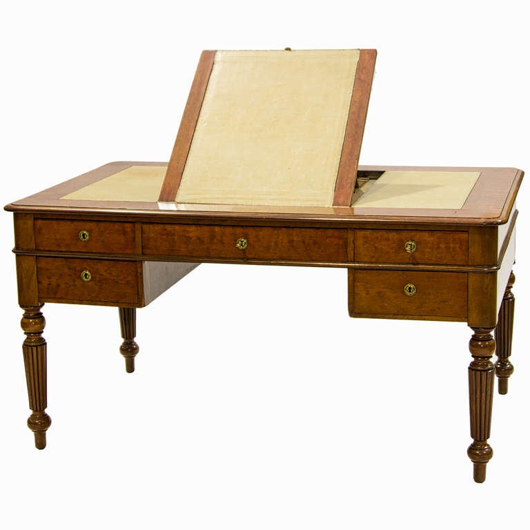 A fine 19th century English Edwardian writing desk. This desk has a center writing surface which lifts up to reveal an adjustable drafting slope. There are three leather inserted panels, each section has blind tooling and the light color of green