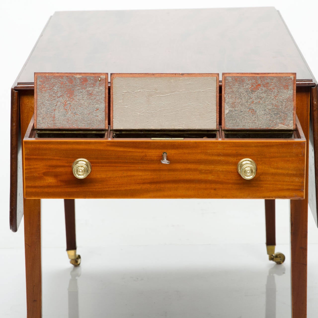 19th century English pembroke table with tea caddies in the drawers.

This table has a wonderful figured mahogany top and tapered legs ending with brass caster feet. Two drop leaves which are supported with two pull-out supports. Subtle in lay to