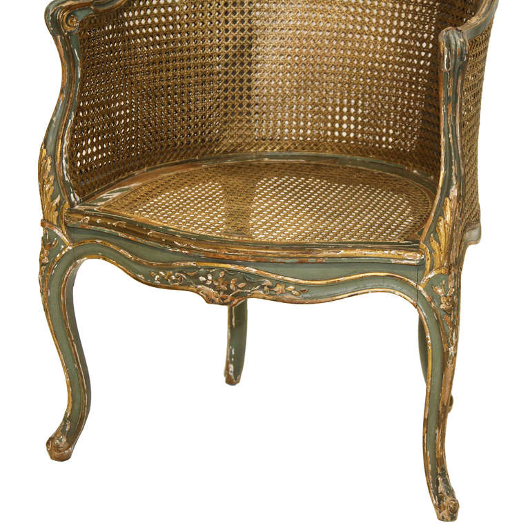 Louis XV Painted Double Cane Back Corner Chair. This chair has a serpentine front and resting on cabriole legs. There are carvings with worn gold highlights. The back panel, we had re-caned. I highlighted the color of it to show. It blends in color