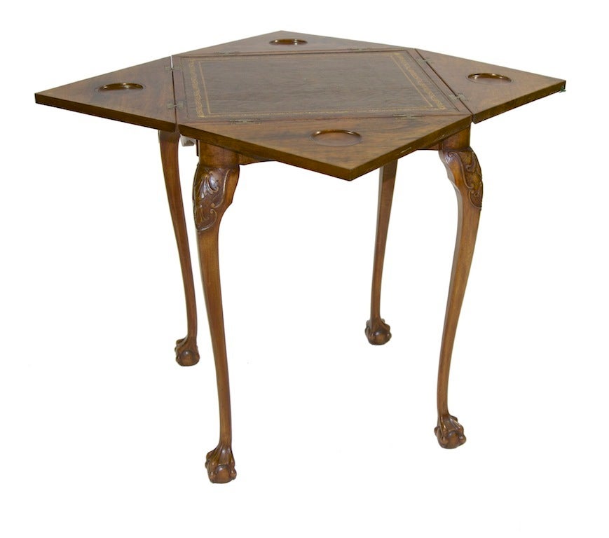 A charming Chippendale style envelope game table. Highly figured burl walnut top and aprons stand out. The top swivels to situate the top square to the base for use. Each tri-folding section is situated with a carved out candle stand. A leather top