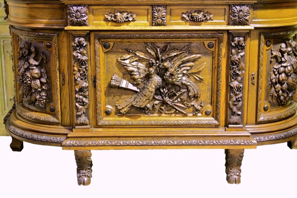 An Amazing oak carved wine cabinet. Excellent carving depicting doves, trophy, grapes and vines, nuts and berries. The pulls are even carved with grapes and vines. There are two drawers above three cabinet doors which open revealing open shelf with