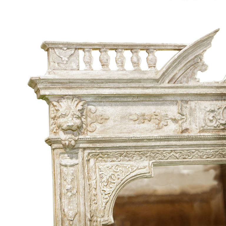 A French neo Renaissance overmantel painted and wood carved mirror. The mirror is topped with a broken arched pediment surrounded by turned balusters and in the center sits a putti faced urn finial. The piece is further decorated by a putti mask
