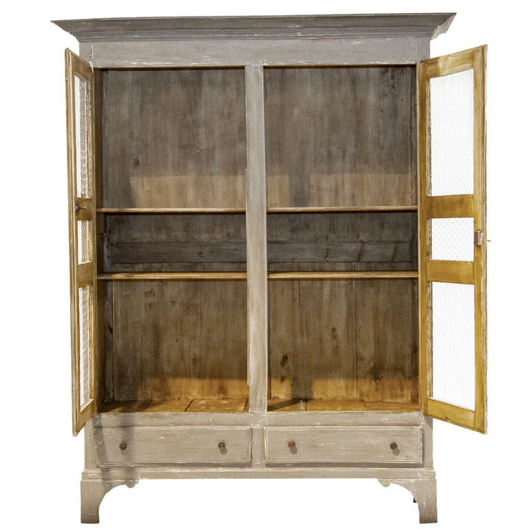 A straight lined and simple painted provincial cabinet with wire fronts and two drawers below. The doors open to two shelves and above is a hanging rod. There are two separate mountable hanging wooded rods with hooks.