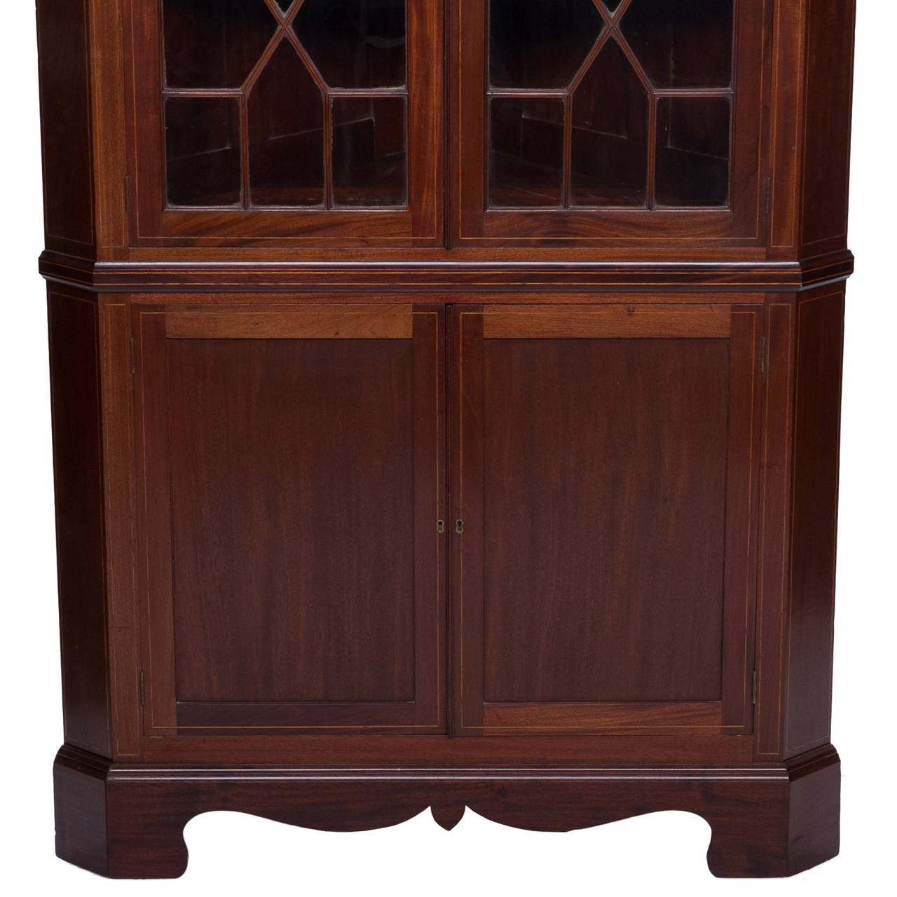 A fine late 19th century Sheraton style mahogany satinwood inlaid corner cabinet with a broken arch pediment. Two doors on the top with mullion and glass front revealing two shelves. Two doors at the bottom which are framed and has a recessed panel