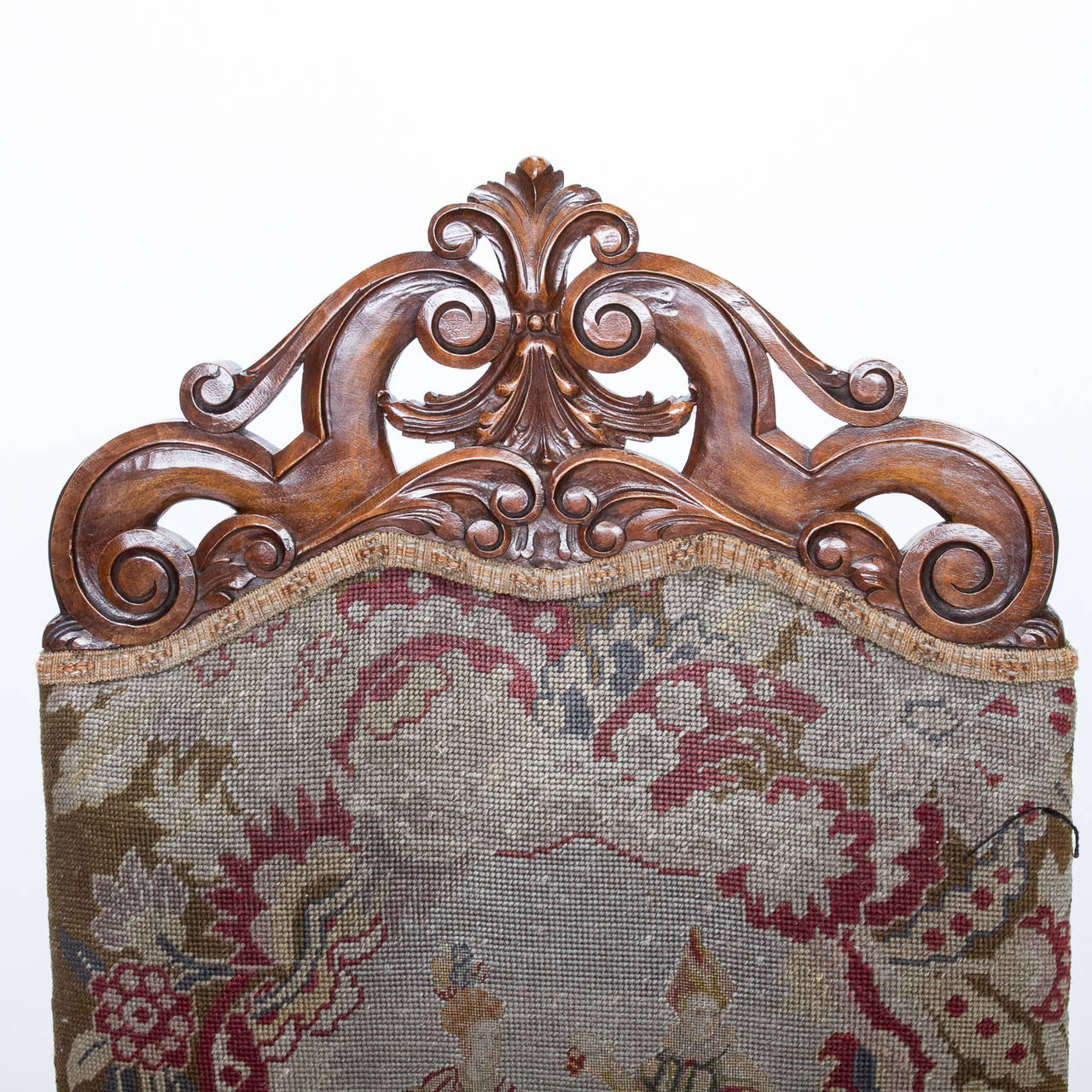 A well carved 19th century walnut framed chair of late 17th century design, turned arm supports, carved apron and turned stretcher, covered in a fine 19th century tapestry. The crest of the chair has a presentation of scroll carvings in an