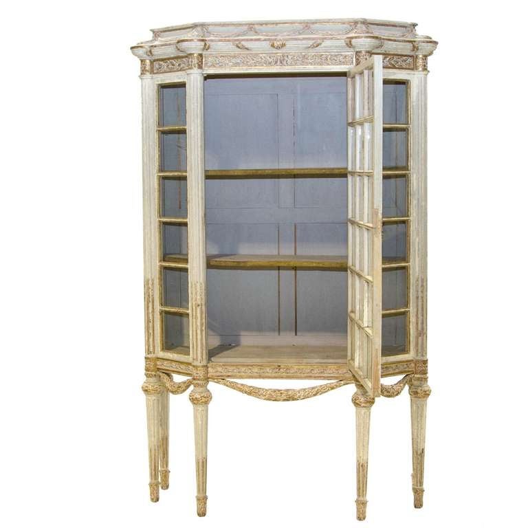 A fantastic Louis XVI style painted curio cabinet from France. Very impressive carving on the crown of this piece. Six reeded columns continuing to the Tapered legs. An incredible set of swags form an apron. The piece is accented with gold