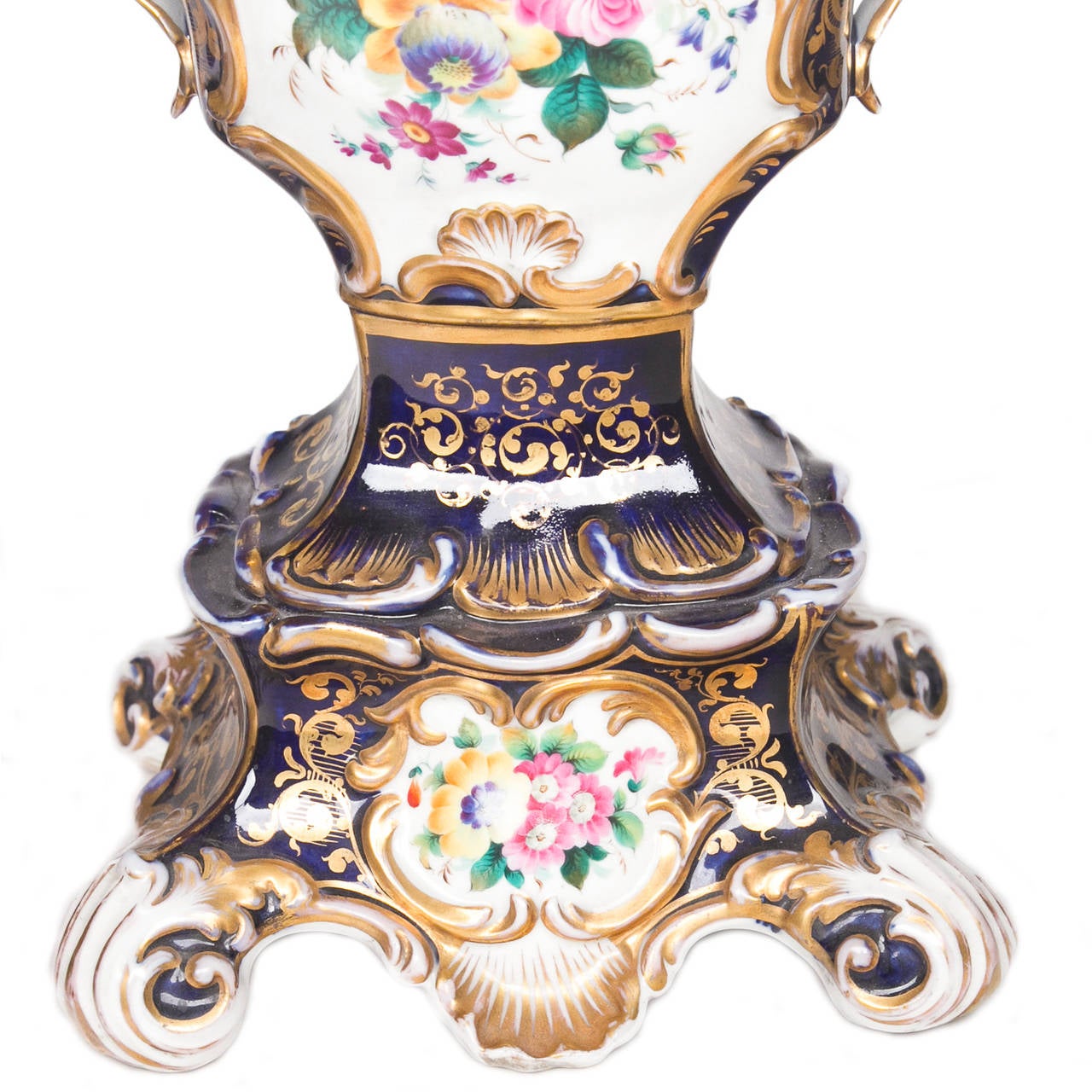 An important pair of old Paris hand-painted urns with scrolled and scalloped designs. These rest on an elaborate base and have pierced handles. Wonderful cobalt blue dominate color. Gilding and strong color palate highlight the urns in floral