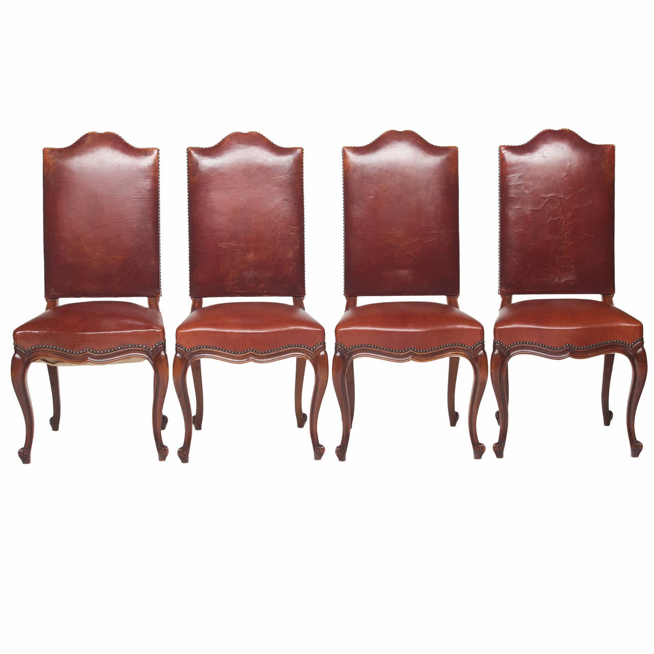 An admirable set of eight Louis XV walnut dining chairs with a distinct shaped crest of the chairs. The backs are all original leather and one seat. The rest have been recovered with a high quality leather. These chairs have a wonderful patina. The