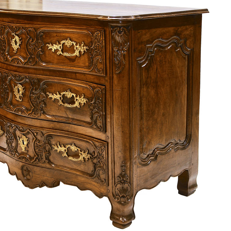 A spectacular 18th century Lyonnaise serpentine front chateau size commode with three drawers and Rococo ormolu hardware. Fantastic wood molding with carvings to enhance the appearance. Raised and beveled sides adorn both sides of the commode.