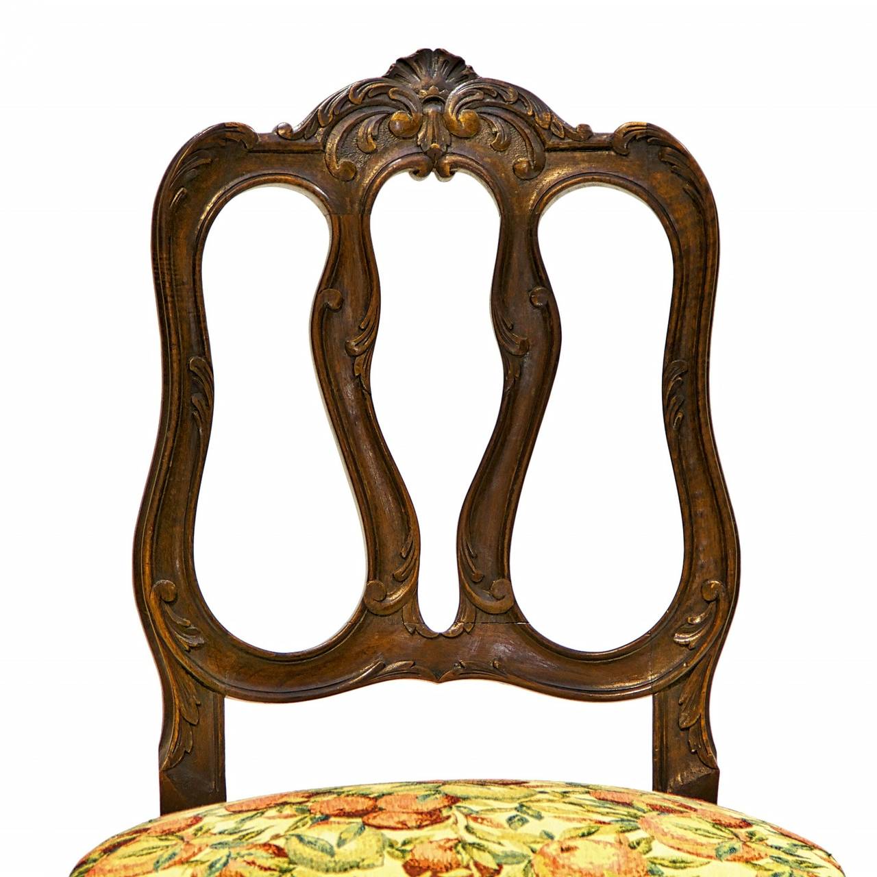 A stylish set of 8 Lyonnaise side chairs made from french walnut. These chairs are in the Louis XV style. The unique and sturdy backs have a shaped splat design. There is a detailed carve shell centered on the apron of the chairs. Elegant cabriole