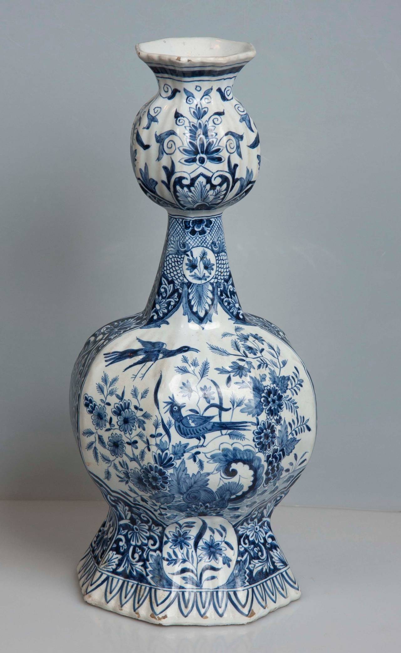 A pair of 19th century Dutch Delftware blue and white round form vases depicting scenes of birds and flowers.
