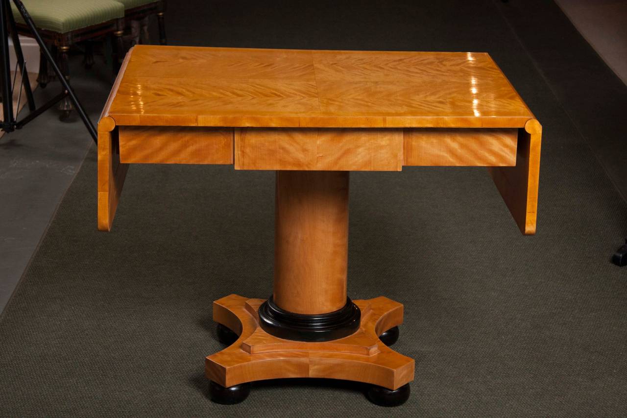 Handsome Biedermeier satinwood sofa table with drop leaves and ebonized detail.