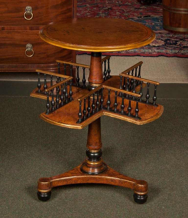 An ebony and burr walnut, two tier book table with molded edge above a shaped under tier with a spindle gallery.