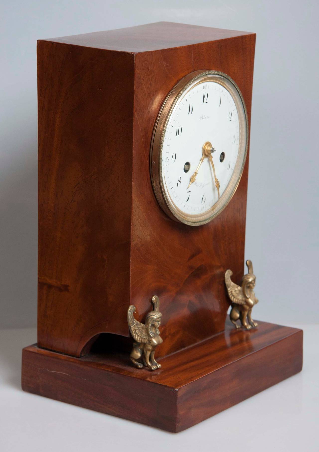 A 19th century French Empire mahogany mantel clock with a circular white enamel dial and Arabic numerals, signed 