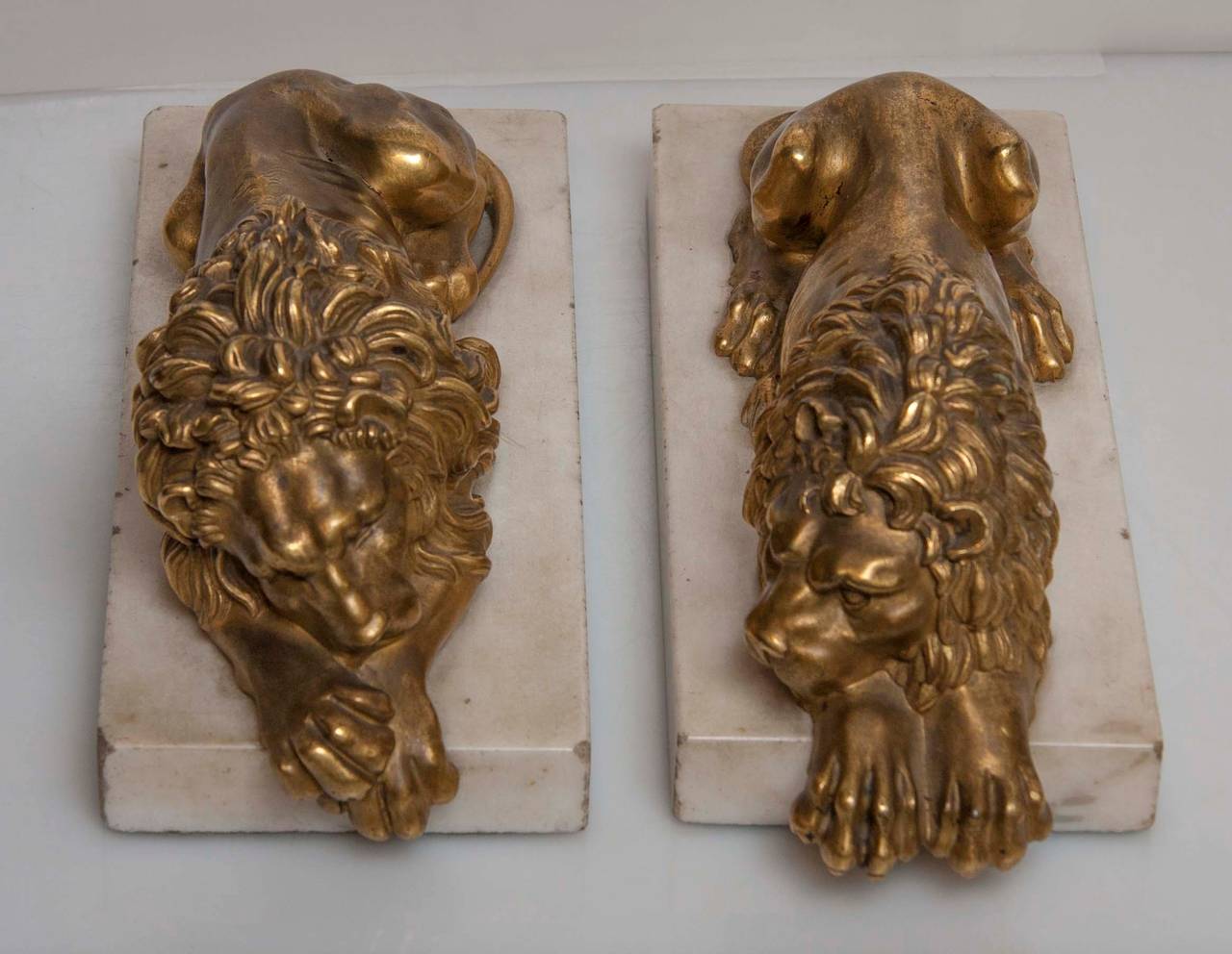 A pair of gilt and bronze recumbent lions on marble bases, after A. Canova.