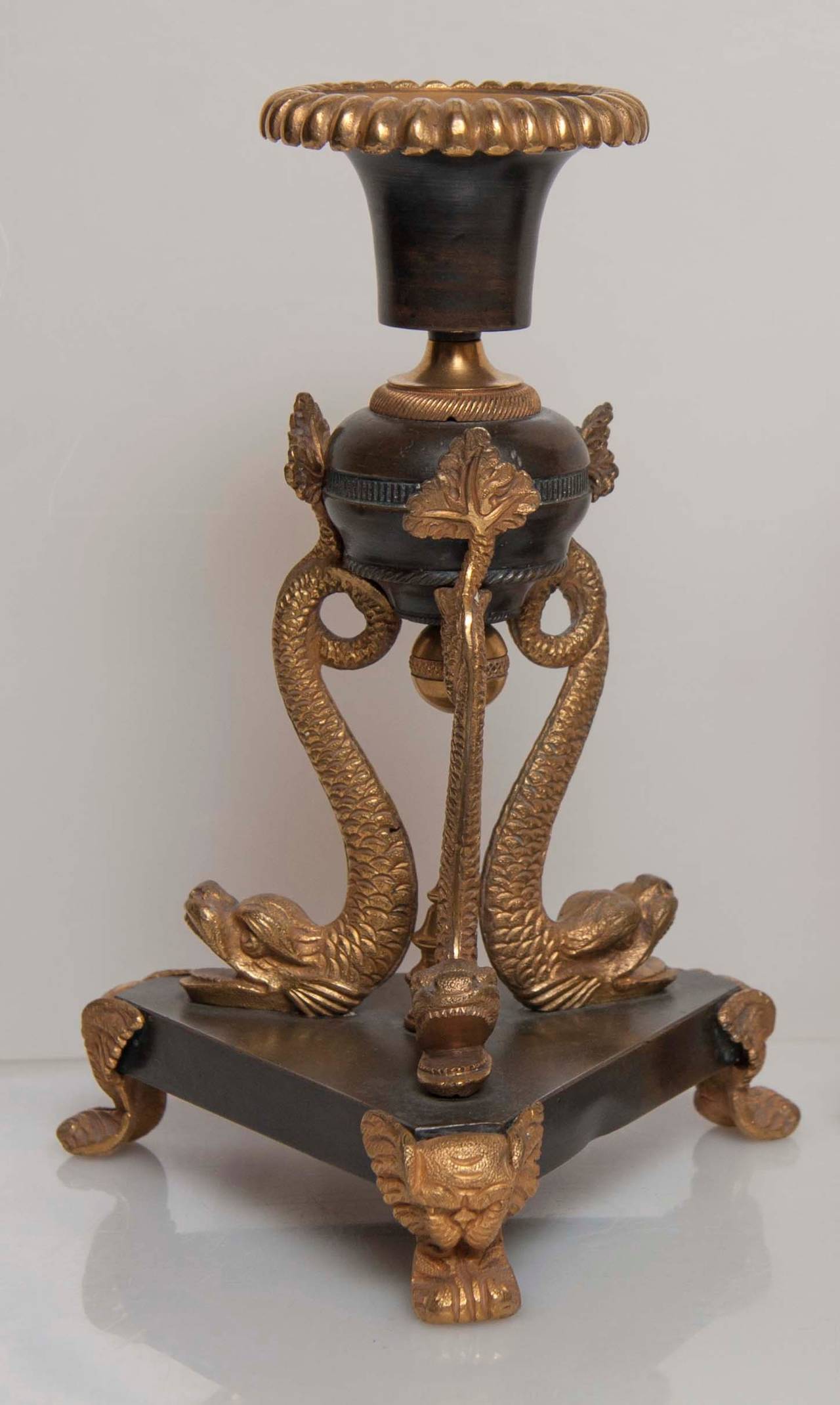 An unusual pair of Regency bronze and ormolu candlesticks with triangular form bases..