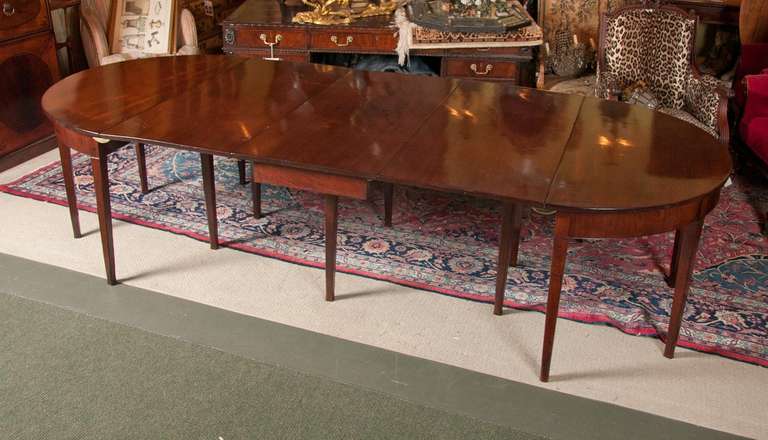 An English, Georgian, D-end, gate leg dining table made of fine quality solid Caribbean crotch mahogany in excellent condition with two leaves of 23 inches each.  Two D-ends of 24 inches each. Middle section of 22.3 inches.  Fully extended, 116.3